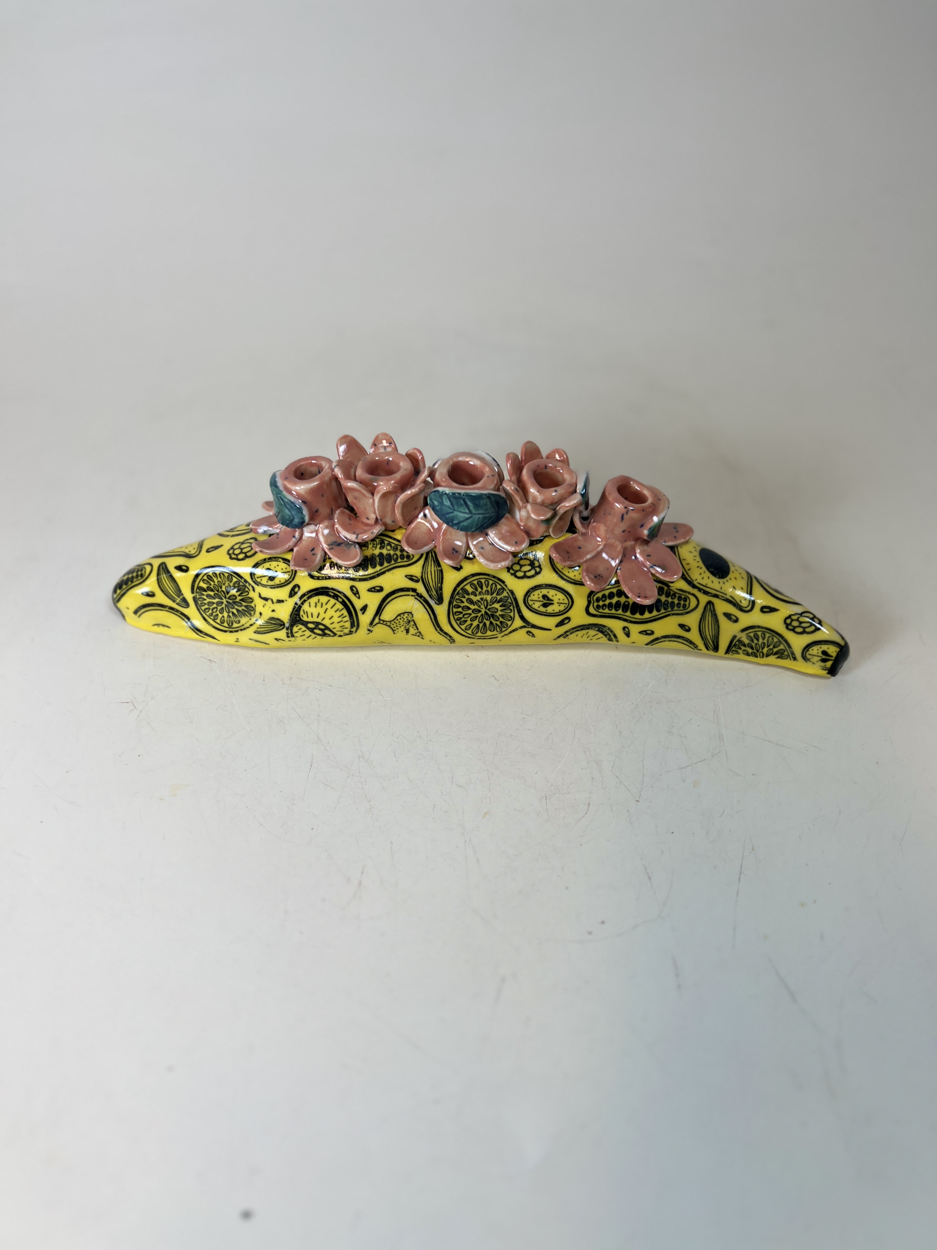 Yellow ceramic candelabra with citrus pattern and pink sculptural rose bud candle holders